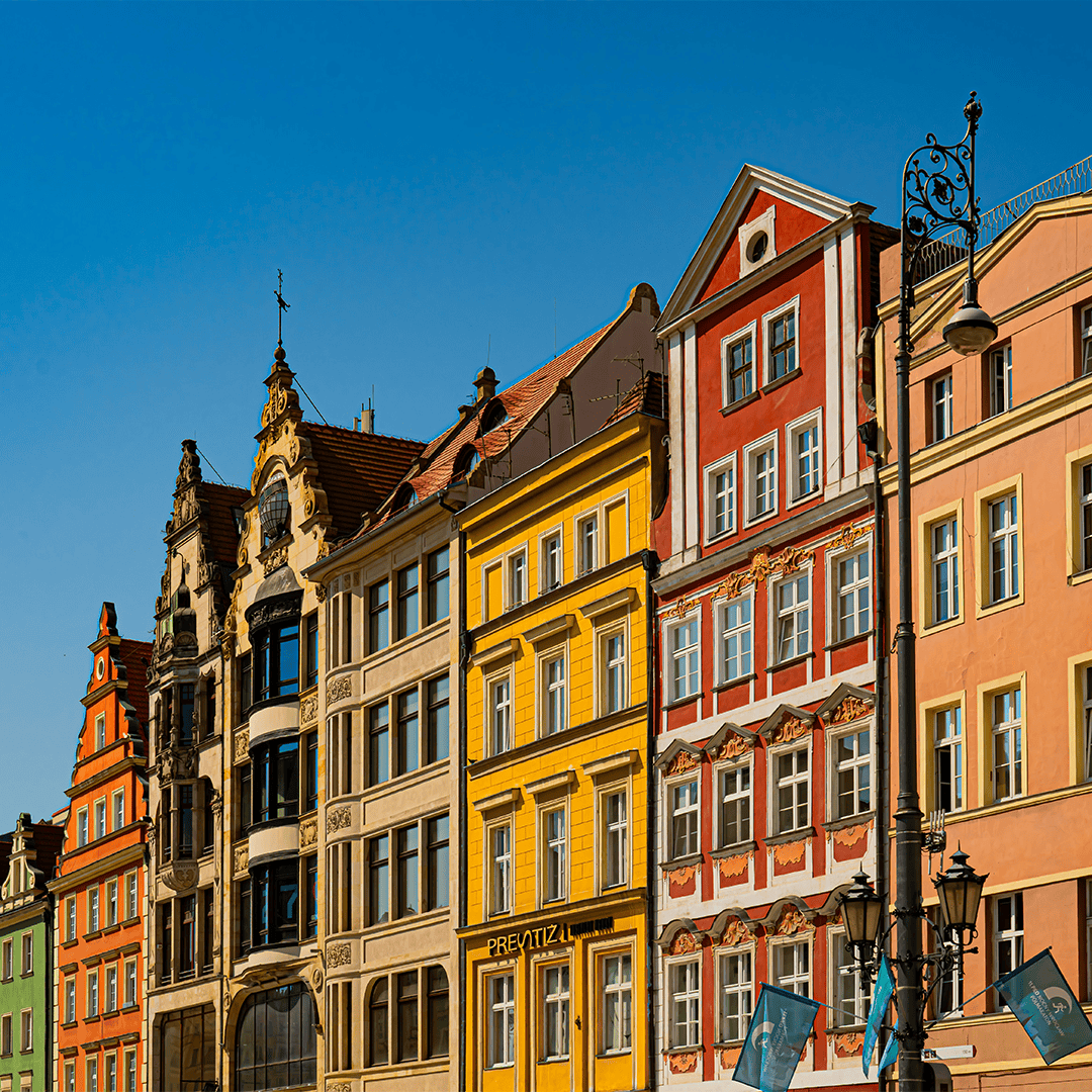 Colorful buildings with ornate facades and pitched roofs under a clear blue sky.