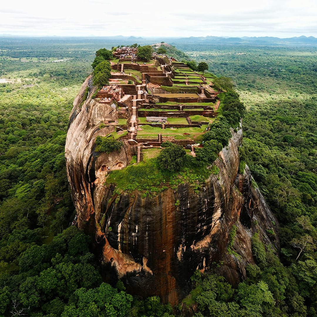 Zoomed out image of Sigiriya Rock Fortress in Sri Lanka surrounded by lush greenery