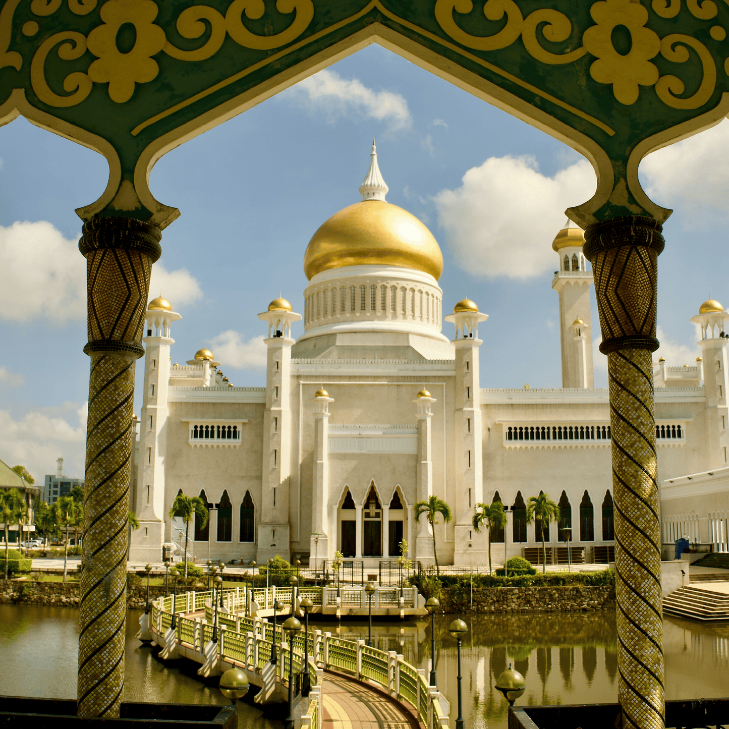 The Omar Ali Saifuddien Mosque in Brunei, framed by ornate green and gold archways, with its iconic golden dome and white minarets reflecting under a blue sky.
